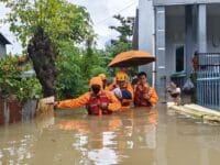 Petugas BPBD Makassar melakukan evakuasi terhadap seorang bayi yang menjadi korban banjir.