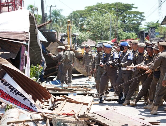 RELOKASI. Anggota Satpol PP menertibkan pedagang kaki lima yang berdagang di bahu jalan di Kecamatan Ujung Tanah, Makassar.